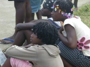 Two children sitting on the ground with their hands crossed.