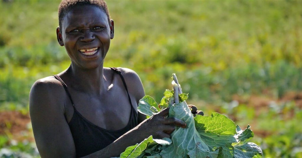 A woman holding up some green vegetables in her hands.