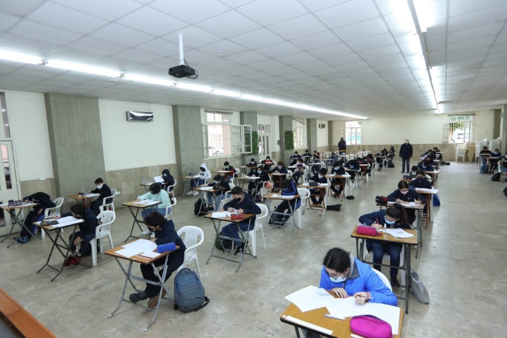 A group of people sitting at desks in an empty room.