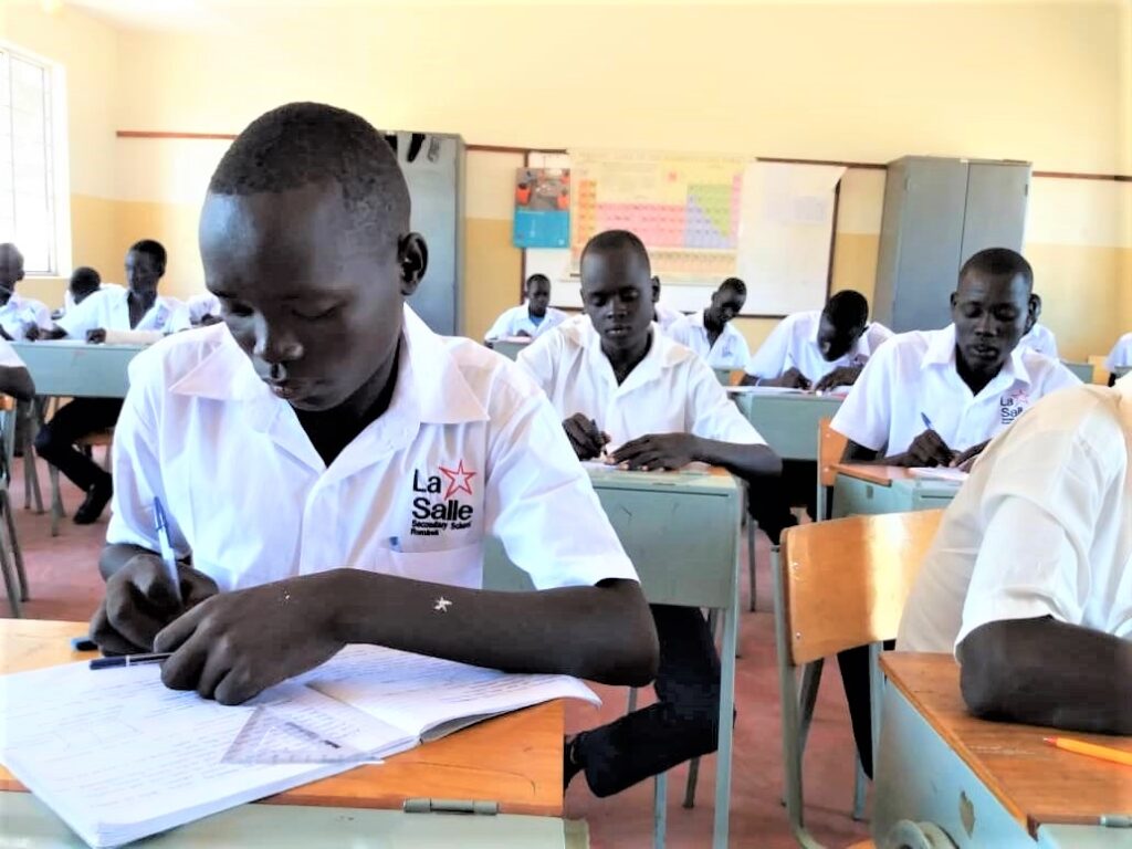 A group of people sitting at desks in front of papers.