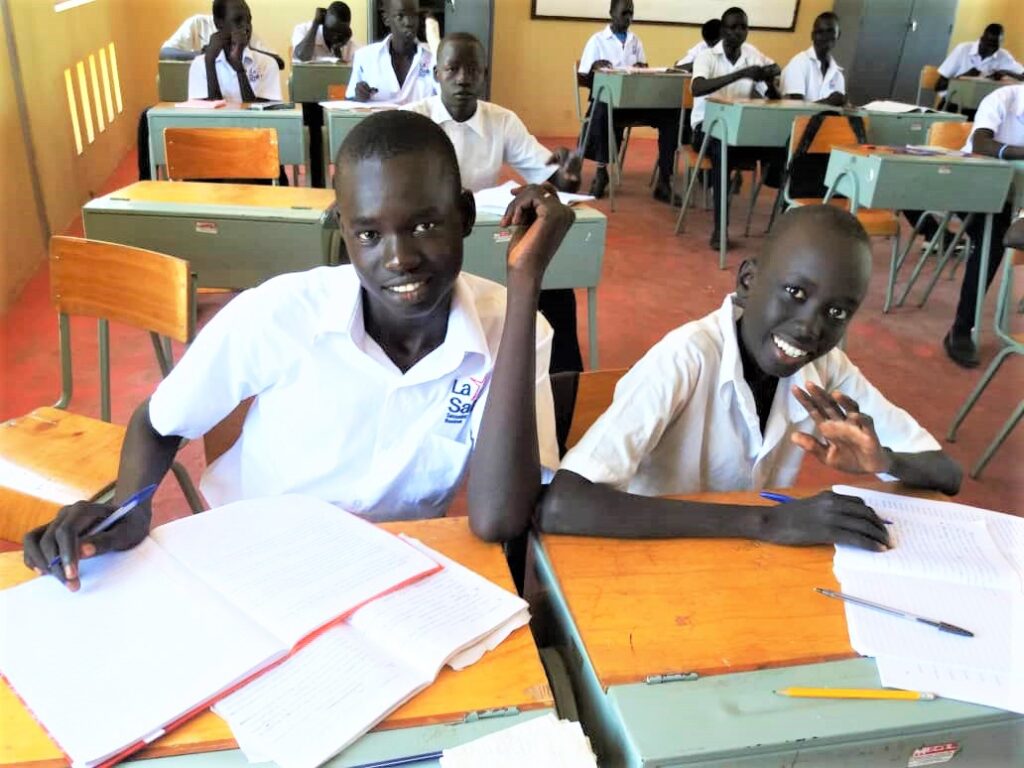 Two boys sitting at a table in front of papers.