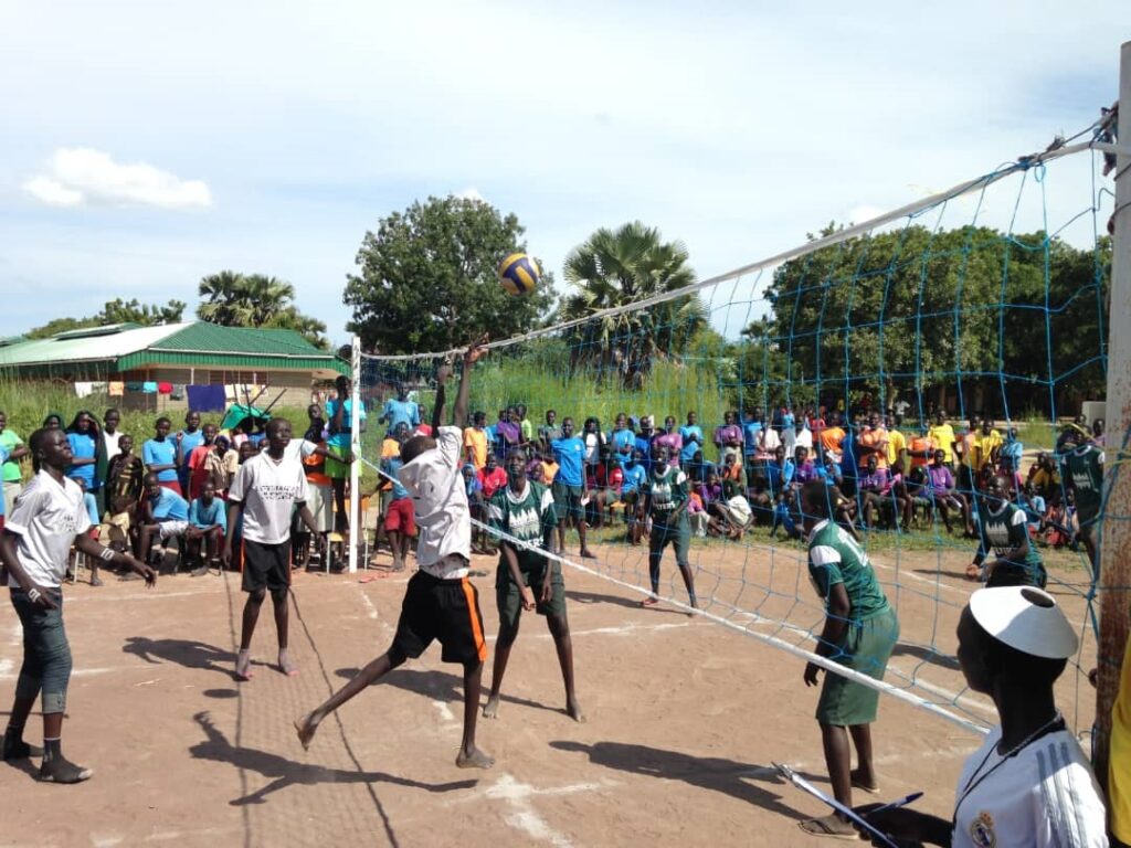 A group of people playing volleyball on the court