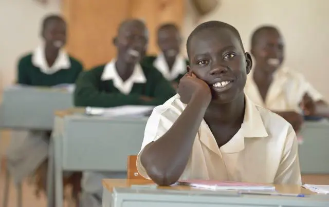 A man sitting at his desk in front of other students.