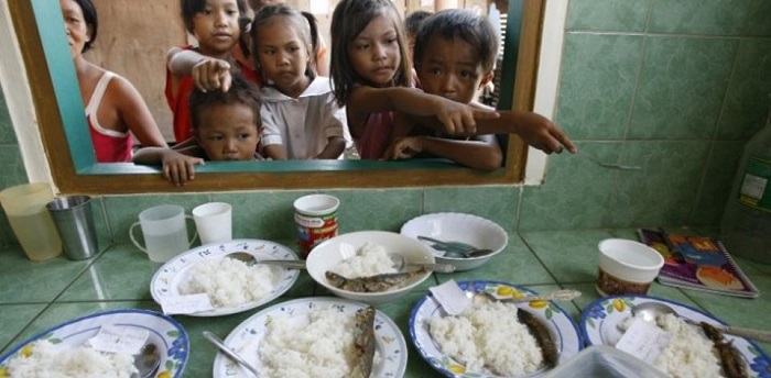 A group of children eating rice and milk.