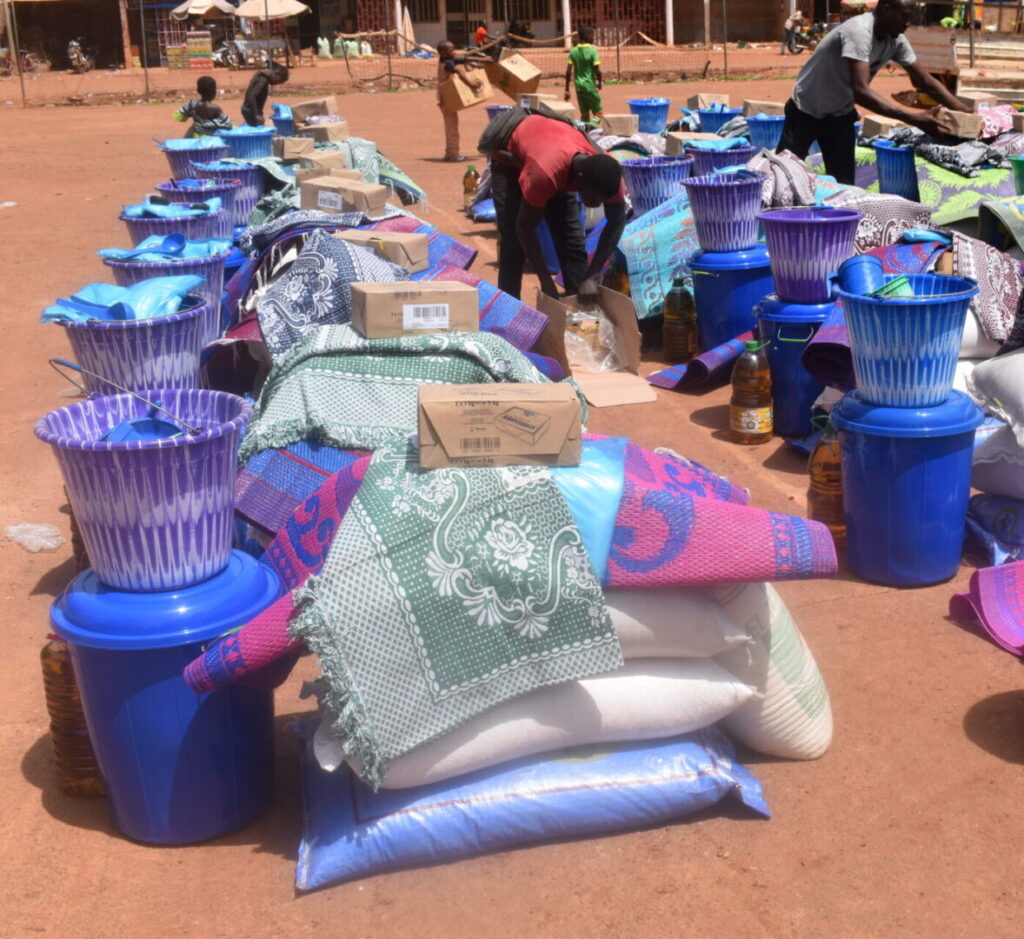 A group of people standing around some blue buckets