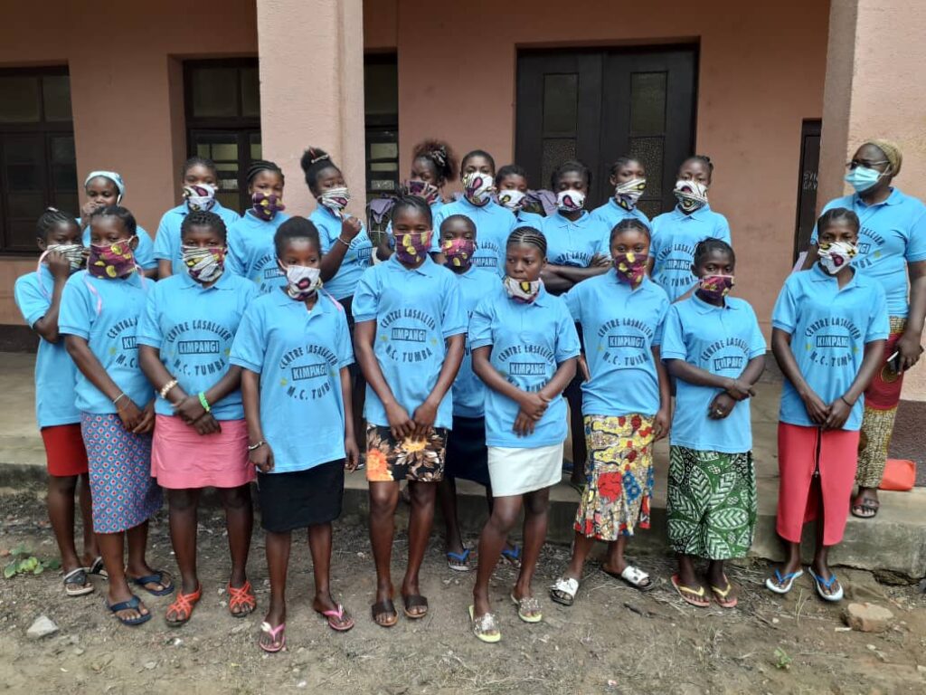 A group of people wearing blue shirts and masks.