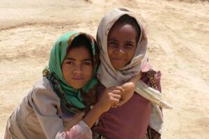 Two young girls in a desert pose for the camera.