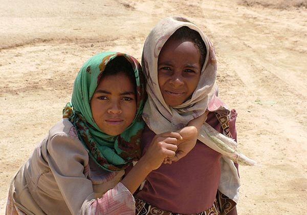 Two young girls in a desert pose for the camera.