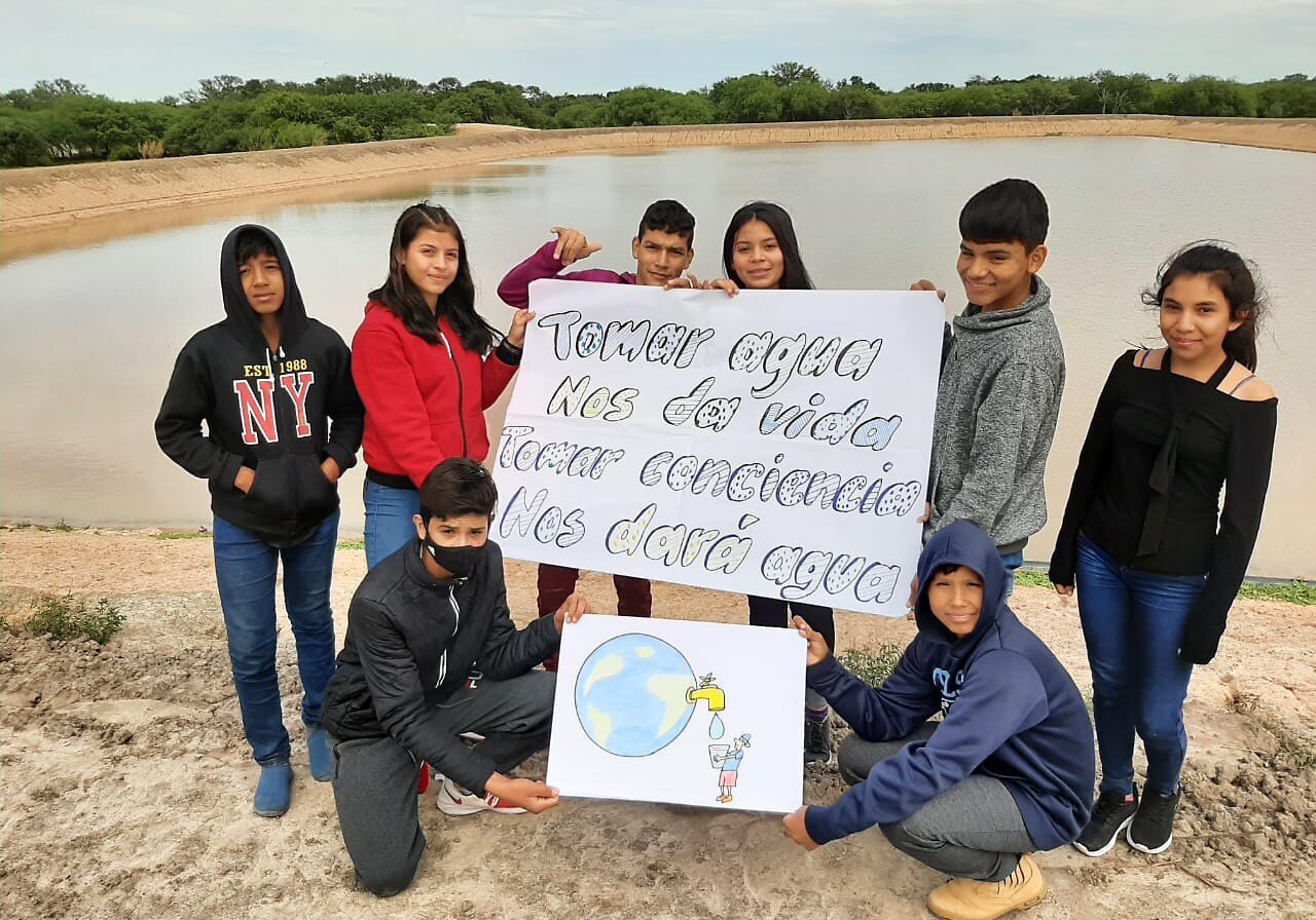 Group holding signs by a pond.